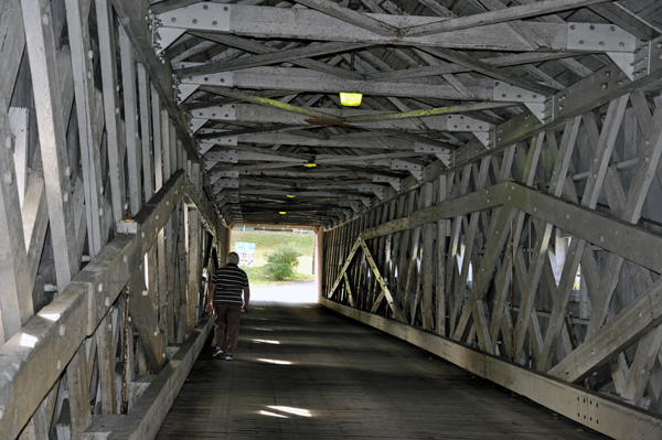 Lee Duquette walking inside The West Cornwall Covered Bridge 